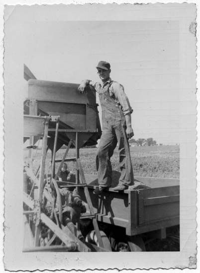 Henry M. Fiegenbaum standing on a wagon next to a combine, c.1945