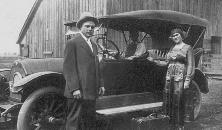 photo of Eugene and Anna (Springmeyer) Gerber standing outside an automobile with a suitcase