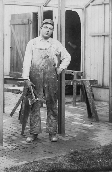photograph of Eugene A. Gerber wearing his work clothes and carrying his carpentry tools